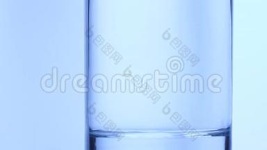 小的圆形物品掉进一杯水里。